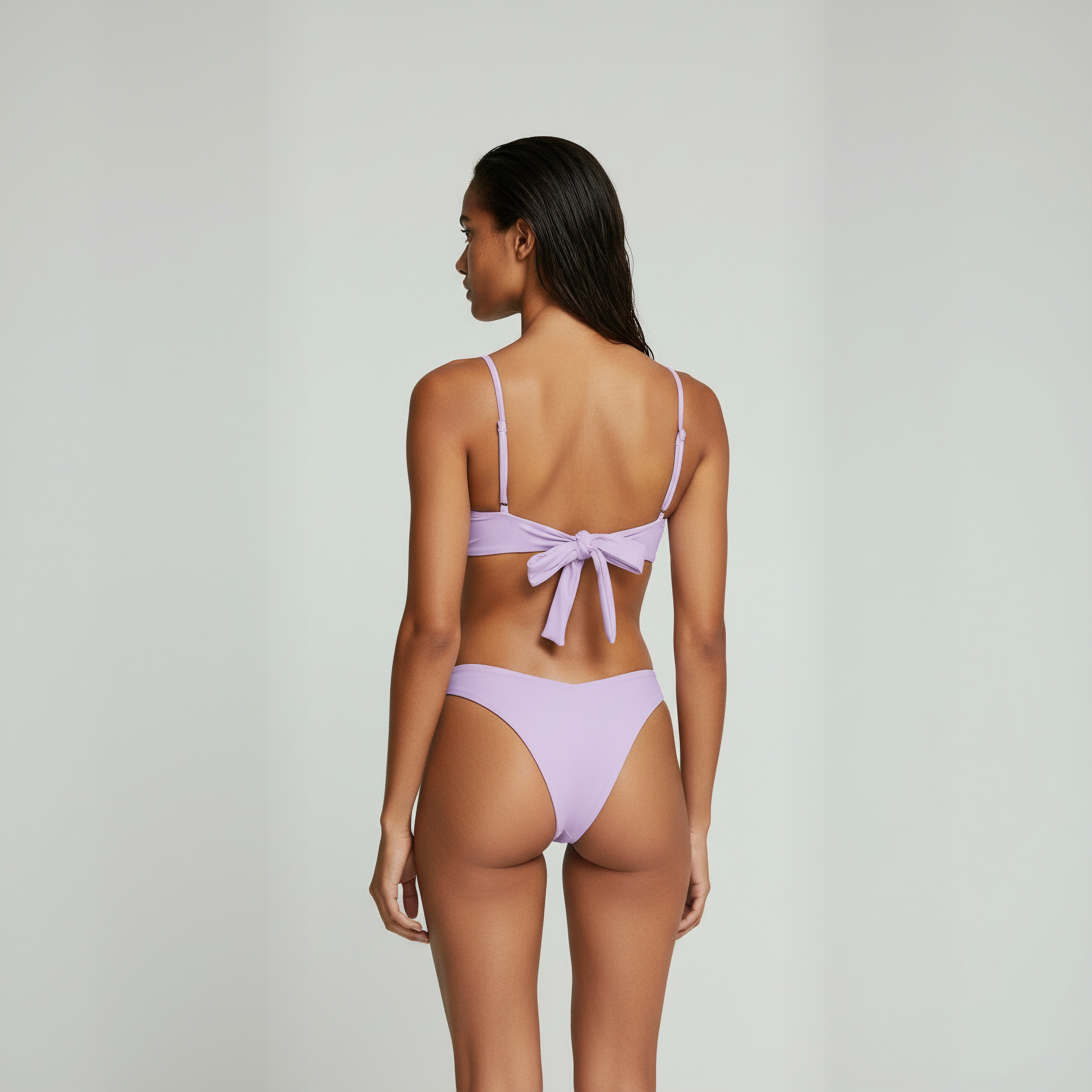 Woman wearing a light purple bikini on a plain background